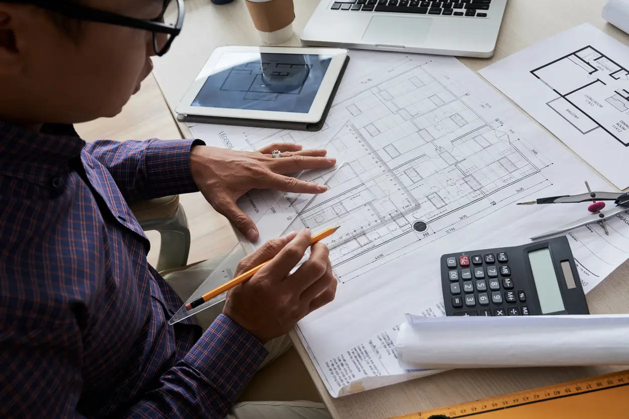 Male architect drawing a blueprint of a building, showing process of digital drawing approach.