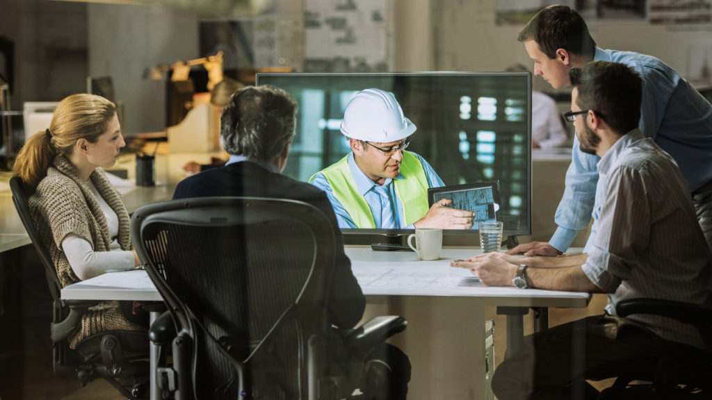 Group of architects and engineers in a conference room discussing the importance of paperless plans.