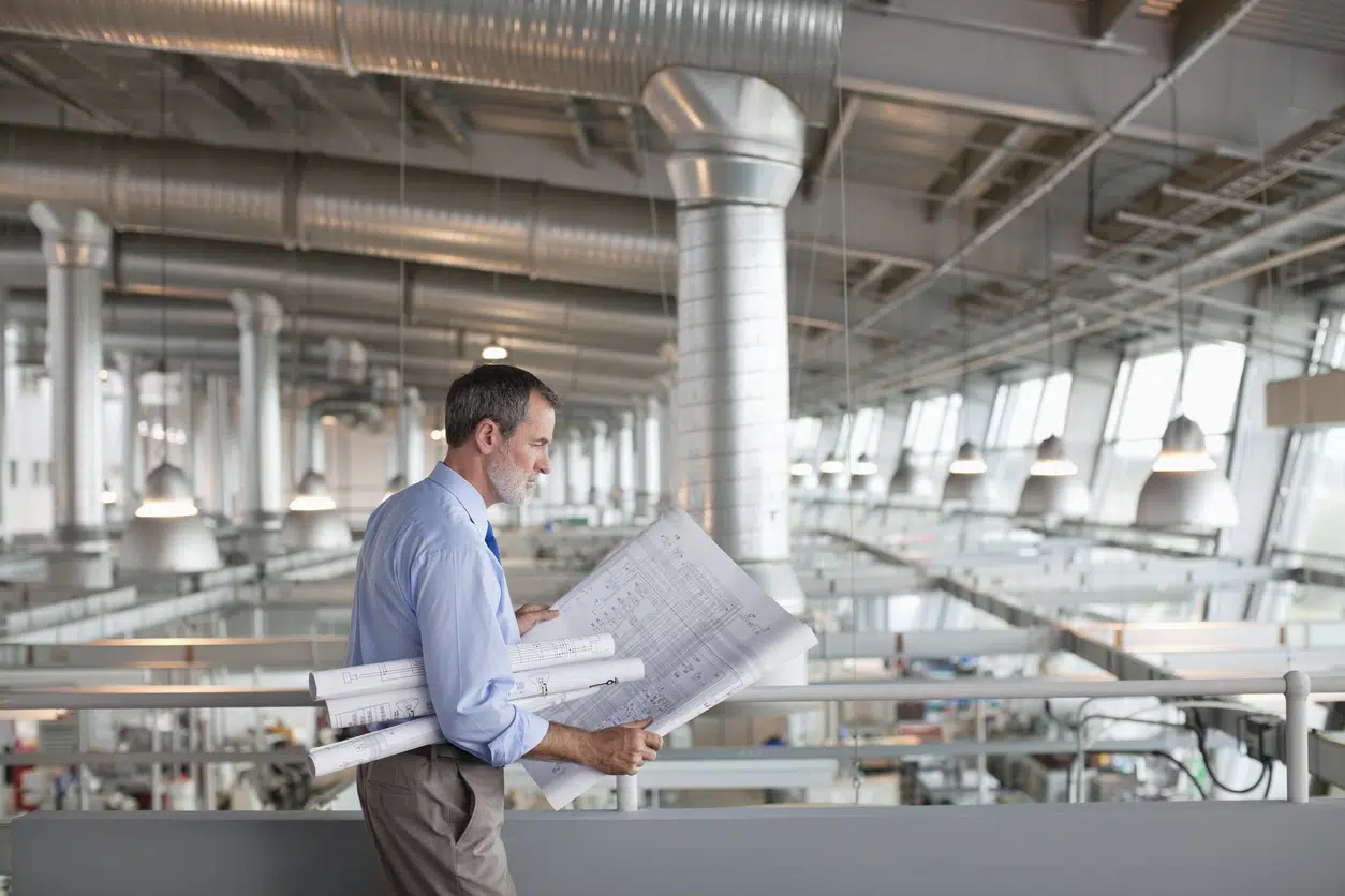 Male facility manager holding several blueprints - showing a concept of blueprints security.