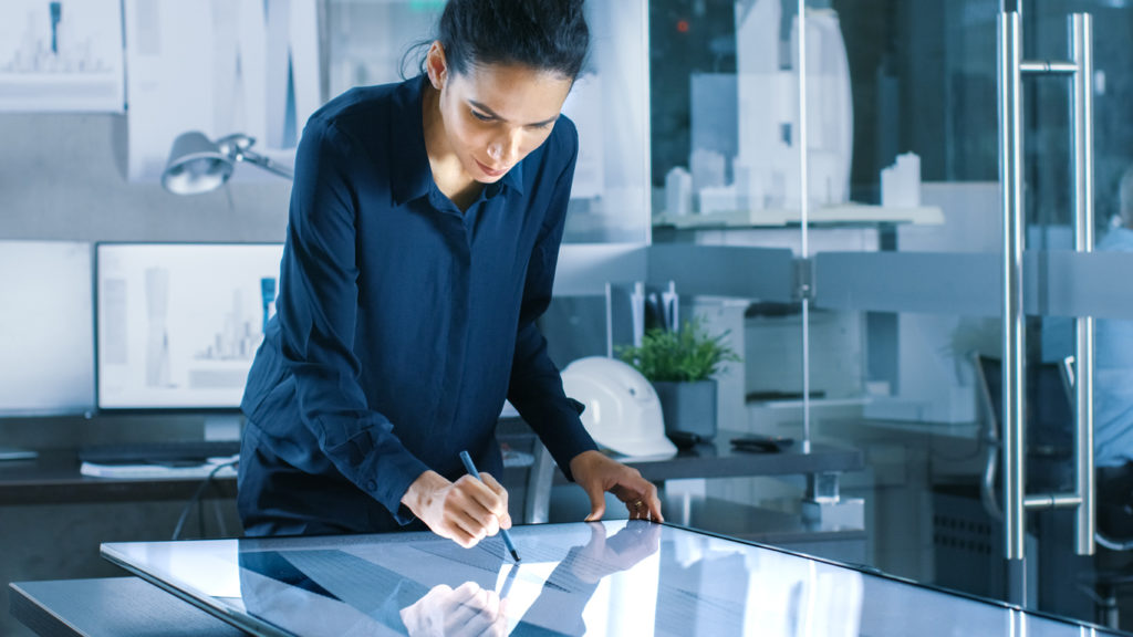 Female architect using a tablet computer to manage a facility's digital blueprints security.