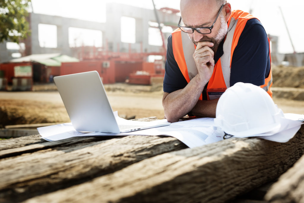 DCM echo - a man using a laptop at an outdoor construction site to access drawings from cloud storage.