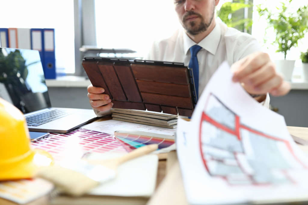 Male engineer checking outdated engineering blueprints to review infrastructure construction.